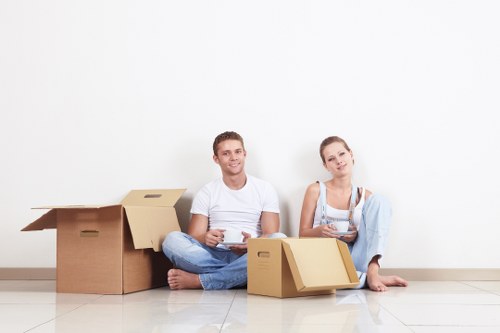 Local movers carrying household items from an Acton flat with stair access
